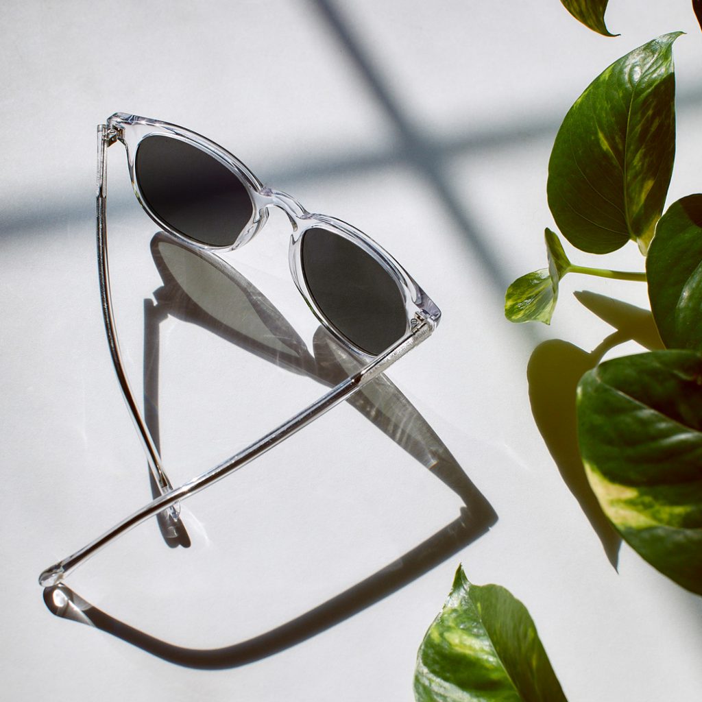 Crystal clear sunglasses next to green leaves