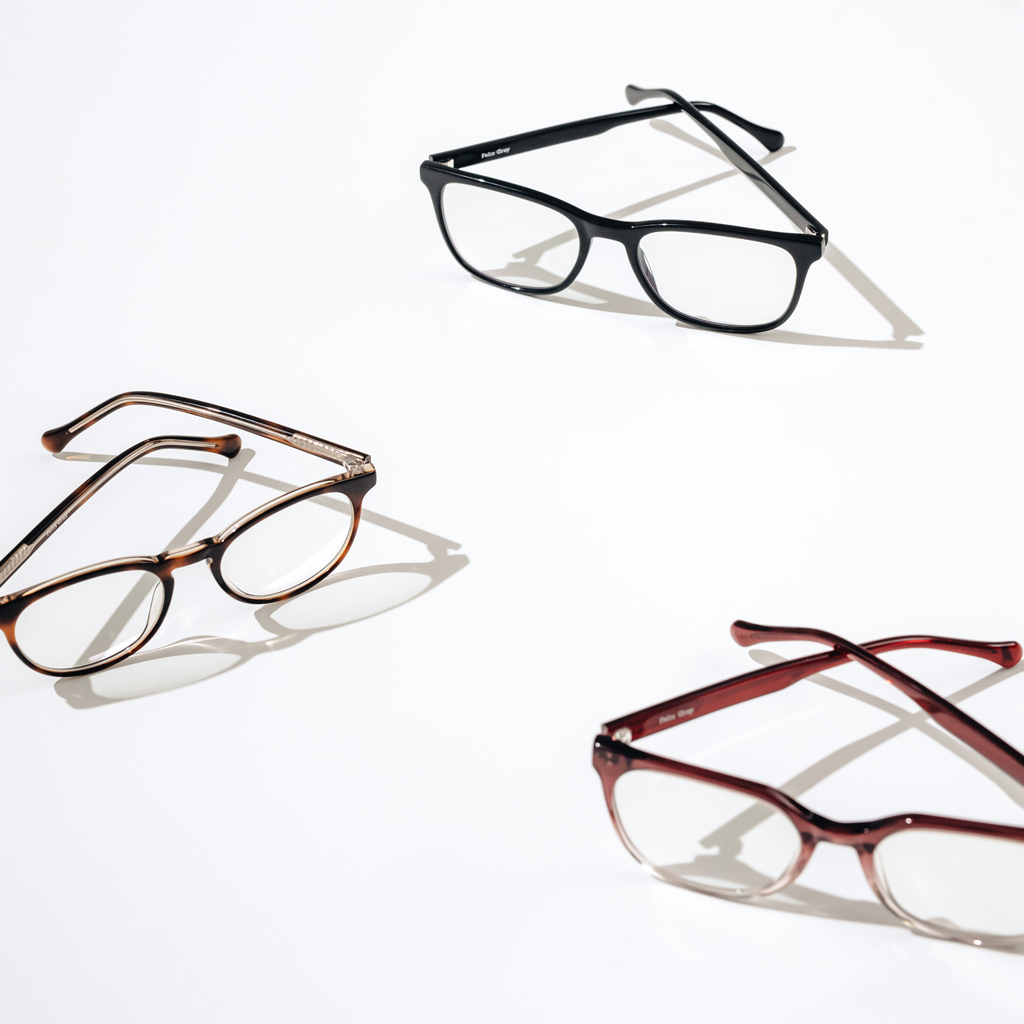 A pair of marron eyeglasses, brown eyeglasses, and black eyeglasses on a white background