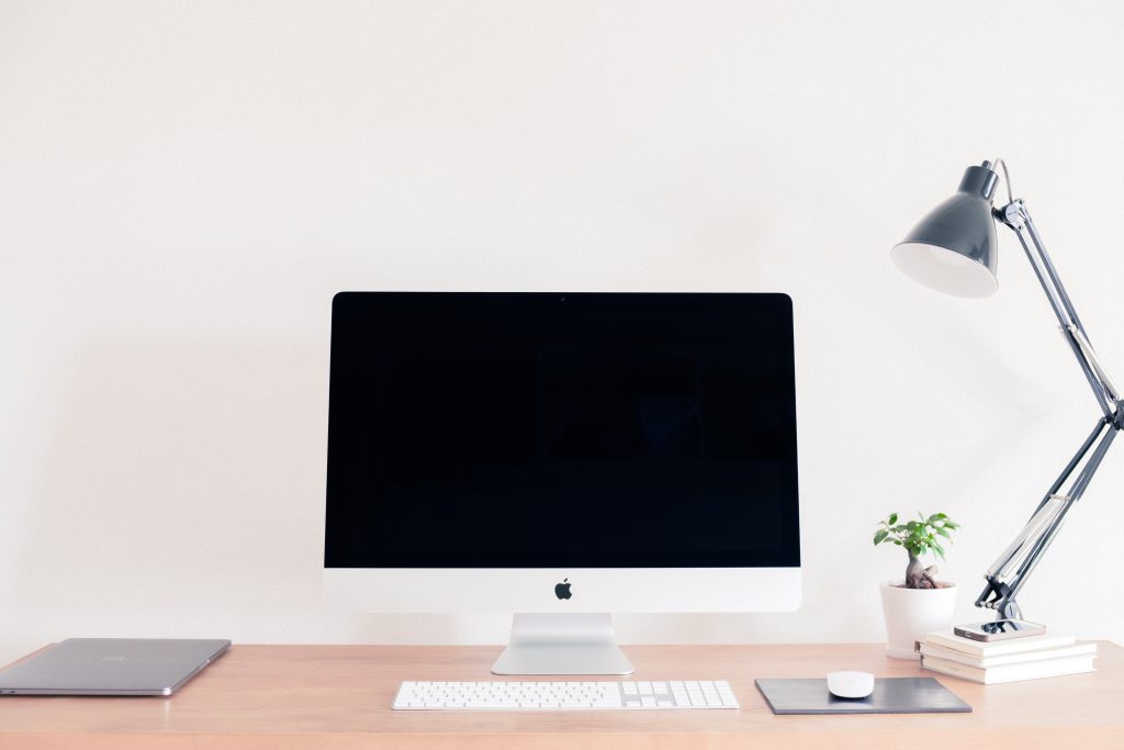 A desk setup with a computer, plant, and lamp