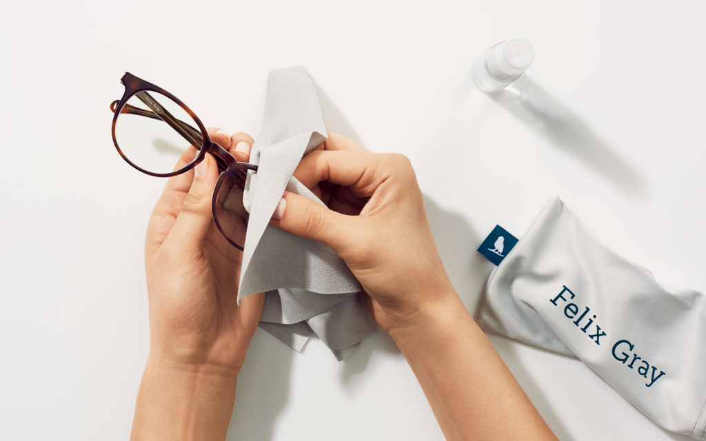 Image of hand cleaning a pair of eyeglasses