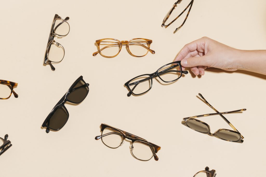 A variety of Felix Gray eyeglasses and sunglasses with a hand coming in