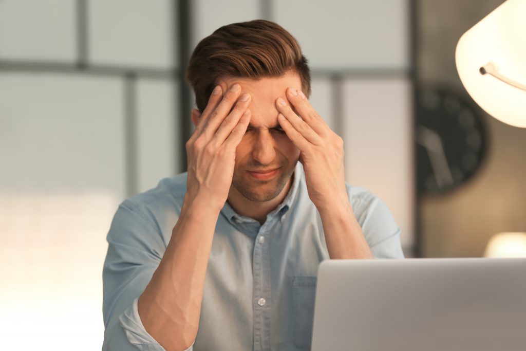 Man with his hands on his head experiencing digital eye strain