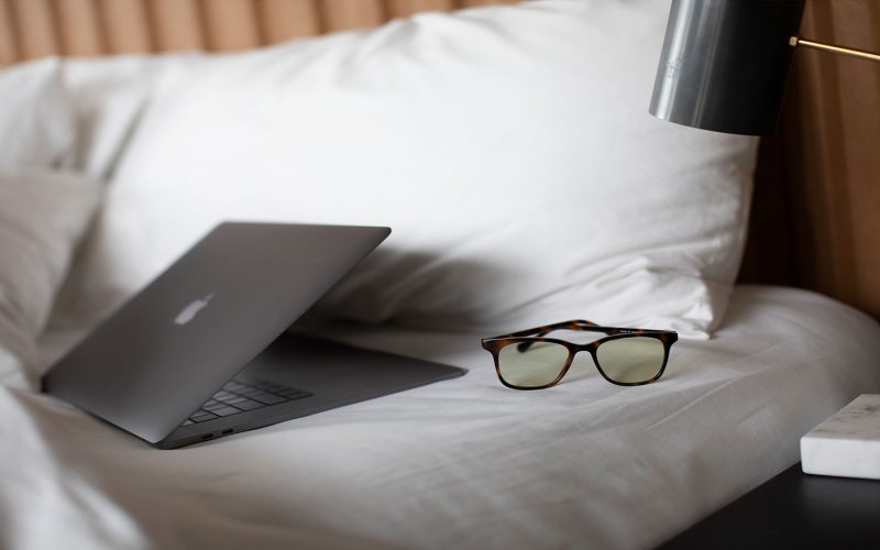 Felix Gray sleep glasses on a bed next to a laptop