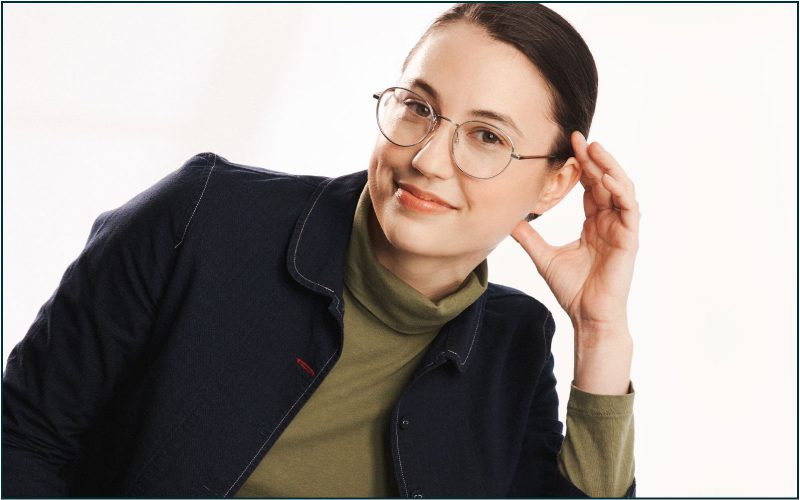 Image of woman smiling leaning on arm wearing silver metal glasses