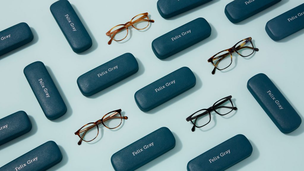 A variety of eyeglasses and teal cases on a blue background