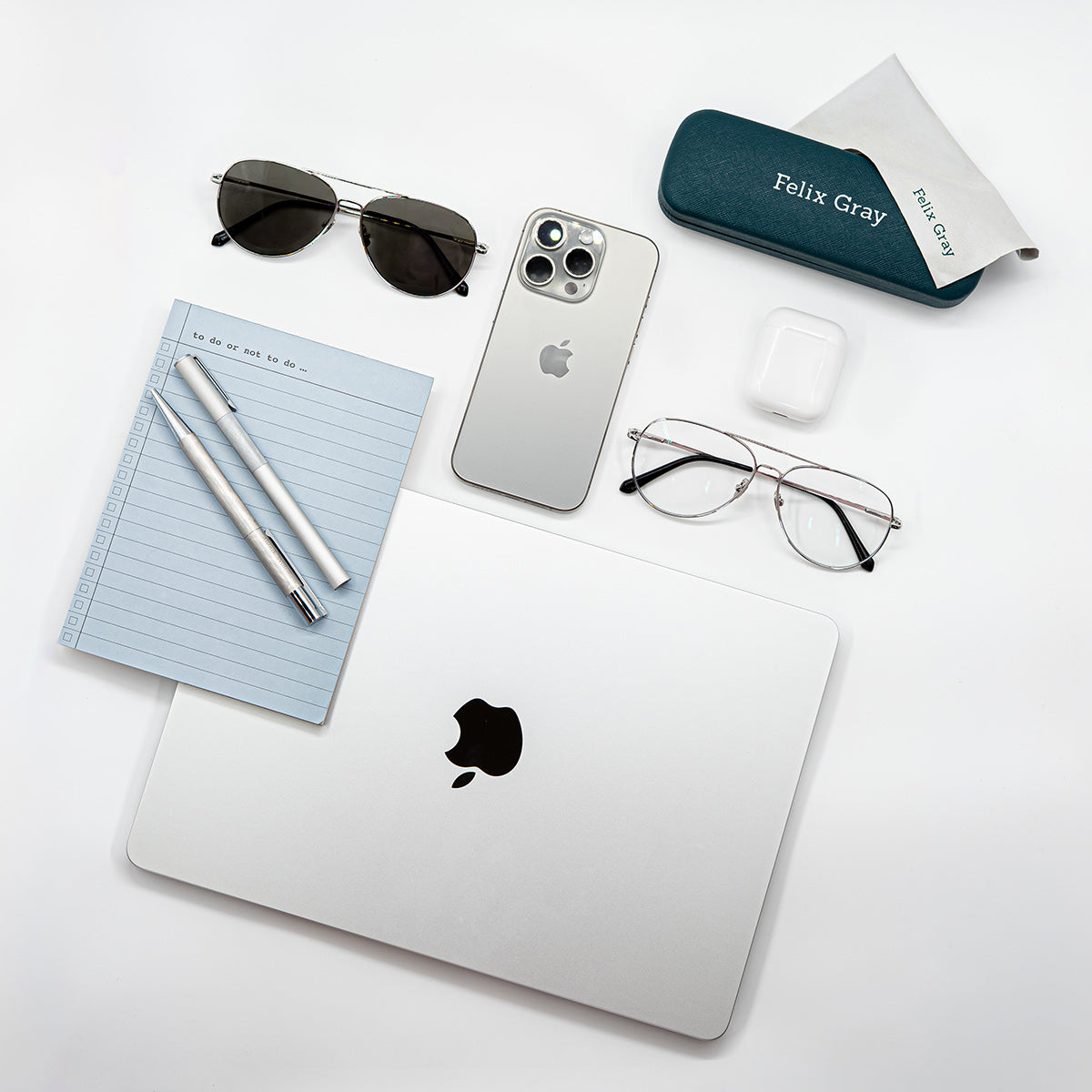 Flat lay image of office supplies, lap top, earphones, glasses, note pad and pens
